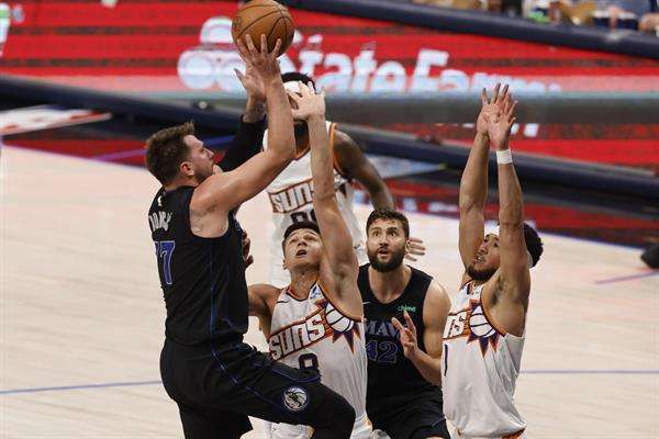 El esloveno Luka Doncic (i), base estrella de los Mavericks de Dallas, fue registrado este jueves, 22 de febrero, al atacar el aro que defienden los Suns de Phoenix, durante un partido de la NBA, en Dallas (Texas, EE.UU.). EFE/Adam Davis