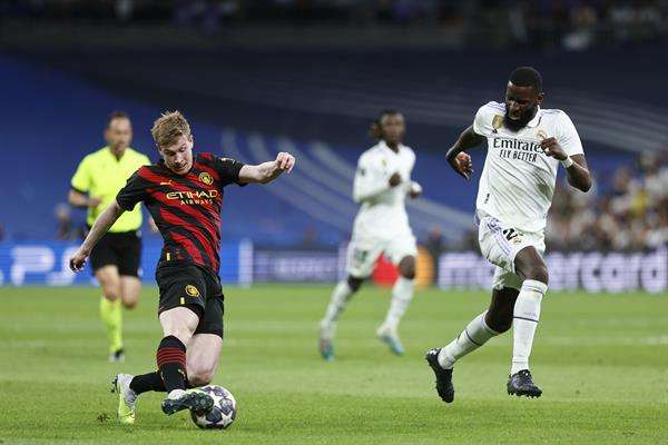 El centrocampista del Manchester City Kevin De Bruyne (i) controla el balón junto a Antonio Rüdiger, del Real Madrid, durante el partido de ida de las semifinales de la Liga de Campeones que Real Madrid y Manchester City disputaron en 2023 en el estadio Santiago Bernabéu, en Madrid. EFE/Rodrigo Jiménez