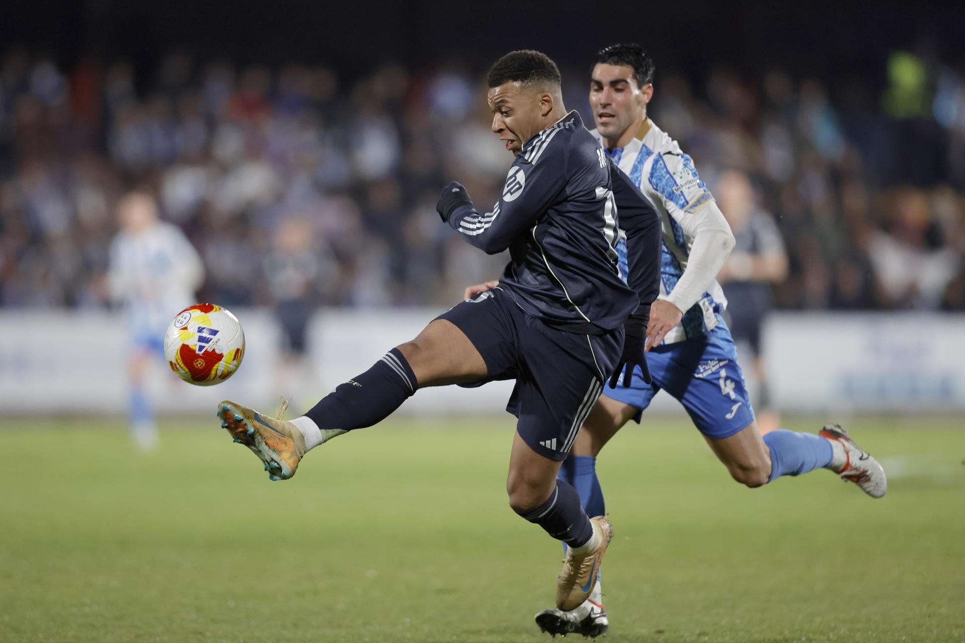 El delantero francés del Real Madrid, Kylian Mbappé, golpea el balón ante el jugador del Talavera, Álvaro López, durante el partido de dieciseisavos de final de la Copa del Rey que Talavera CF y Real Madrid disputaron en el estadio de El Prado. EFE/Manu Reino