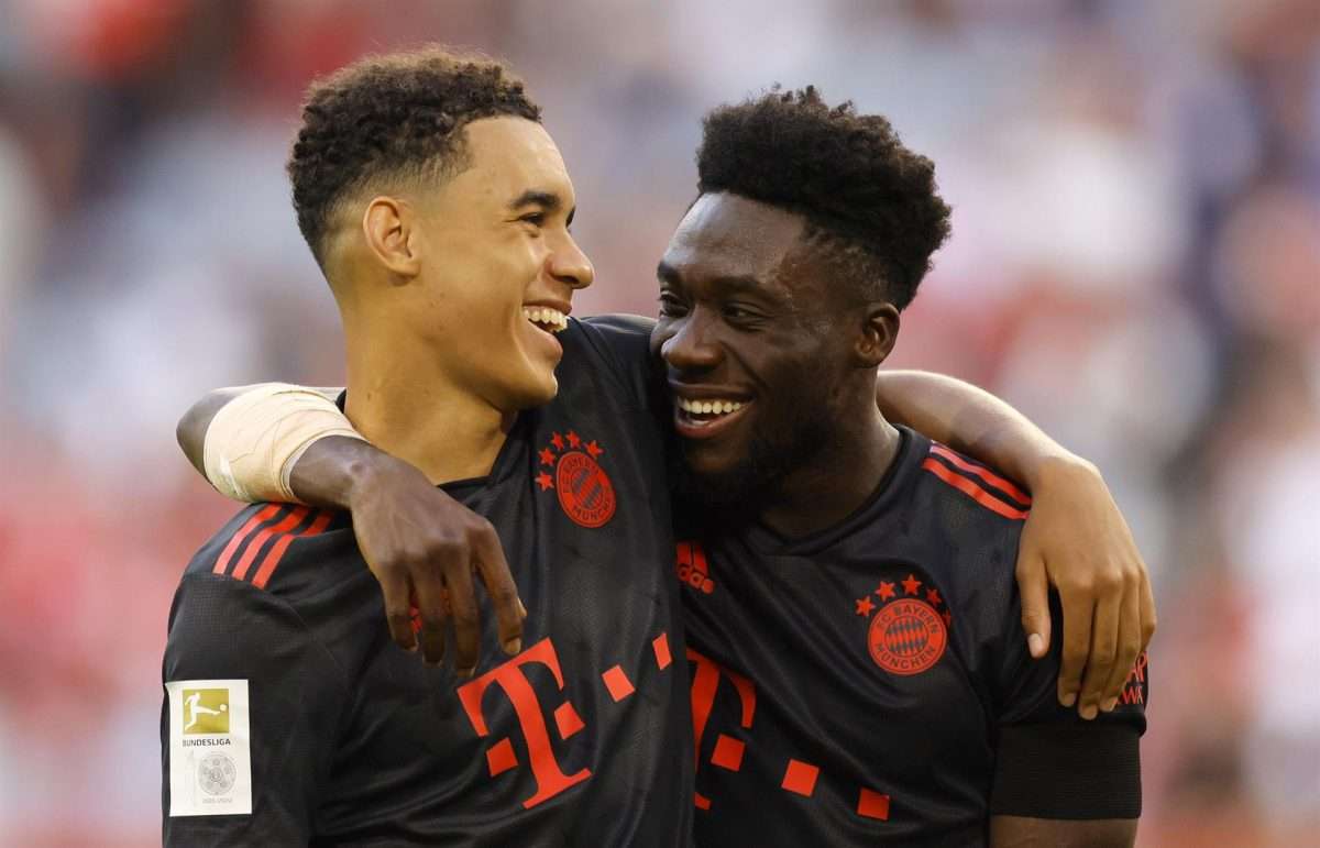 Munich (Germany), 14/08/2022.- Jamal Musiala (i.) and Alphonso Davies (d.) se abrazan tras la victoria de su equipo, el Bayern Múnich contra el Wolfsburgo, en Múnich. EFE/EPA/RONALD WITTEK CONDITIONS - ATTENTION: The DFL regulations prohibit any use of photographs as image sequences and/or quasi-video.
