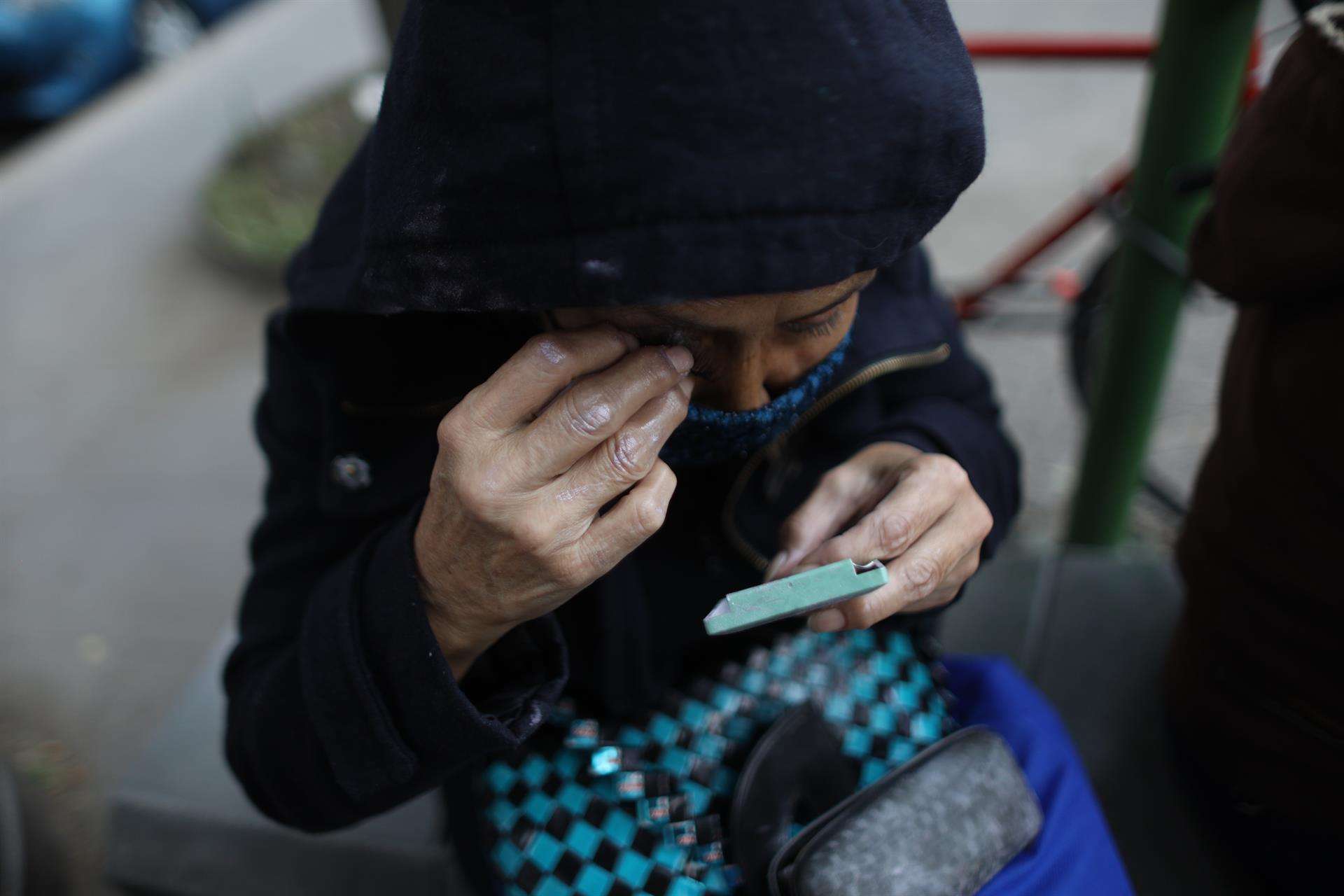 Fotografía de archivo fechada el 2 de junio de 2021 que muestra a una mujer mientras se maquilla en una calle de Ciudad de México (México). EFE/ Sáshenka Gutiérrez