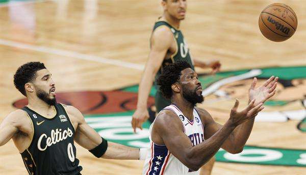 Joel Embiid (d), pívot estrella de los Sixers de Filadelfia, fue registrado este martes, 9 de mayo, al intentar atrapar un balón, ante la mirada de Jayson Tatum (i), de los Celtics de Boston, durante el quinto partido de esta llave semifinal de la Conferencia Este de la NBA, en el coliseo TD Garden, en Boston (Massachusetts, EE.UU.). EFE/CJ Gunther
