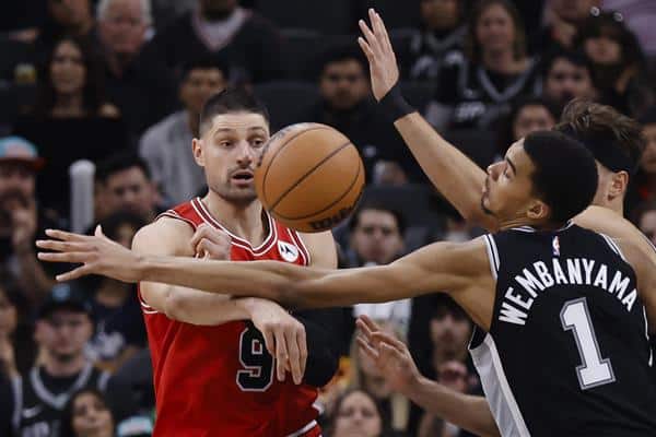 El centro de Chicago Bulls Nikola Vucevic de Montenegro (i) pasa el balón pasando por el centro de San Antonio Spurs Victor Wembanyama de Francia (d) durante la segunda mitad de un partido de la NBA. EFE/EPA/ADAM DAVIS