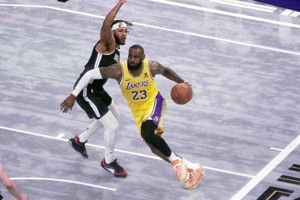 Lebron James (d), alero de los Lakers de Los Ángeles, fue registrado este miécoles, 27 de marzo, al intentar superar la marca de un defensa de los Grizzlies de Memphis, durante un partido de la NBA en el coliseo FedEx Forum, en Memphis (Tennessee, EE.UU.). EFE/Karen Pulfer Focht
