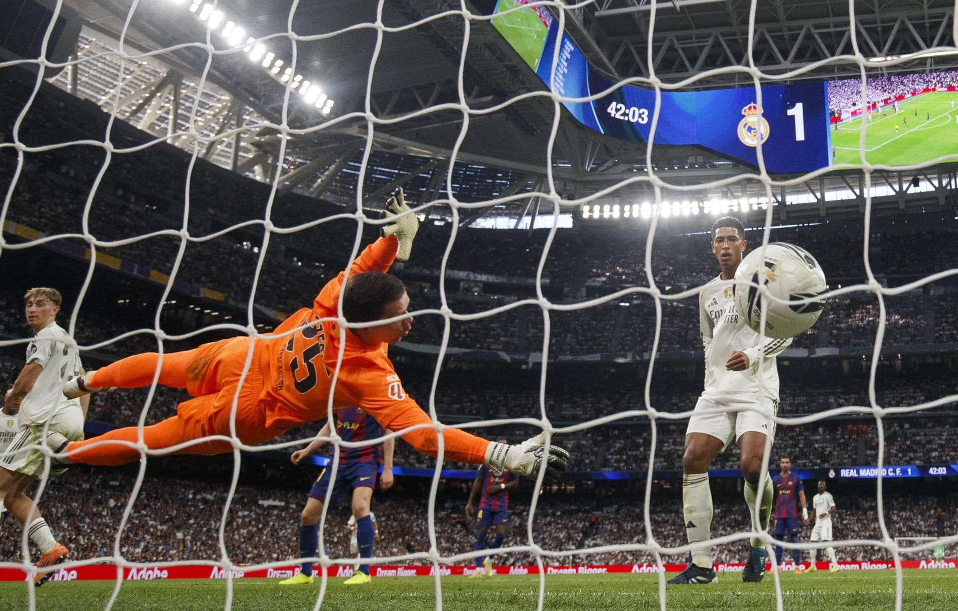 El delantero del Real Madrid Jude Bellimgham, remata para marcar gol ante el portero del Barcelona Wojciech Szczesny, durante el partido de la décima jornada de LaLiga EA Sports, que Real Madrid y FC Barcelona disputaron en el estadio Santiago Bernabéu.EFE/ Sergio Pérez
